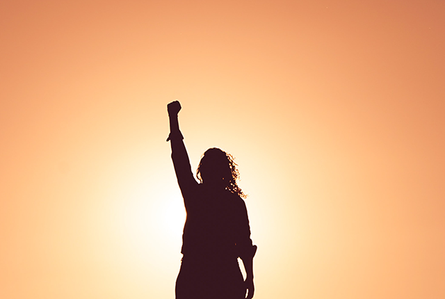 photo of person silhouetted with fist raised